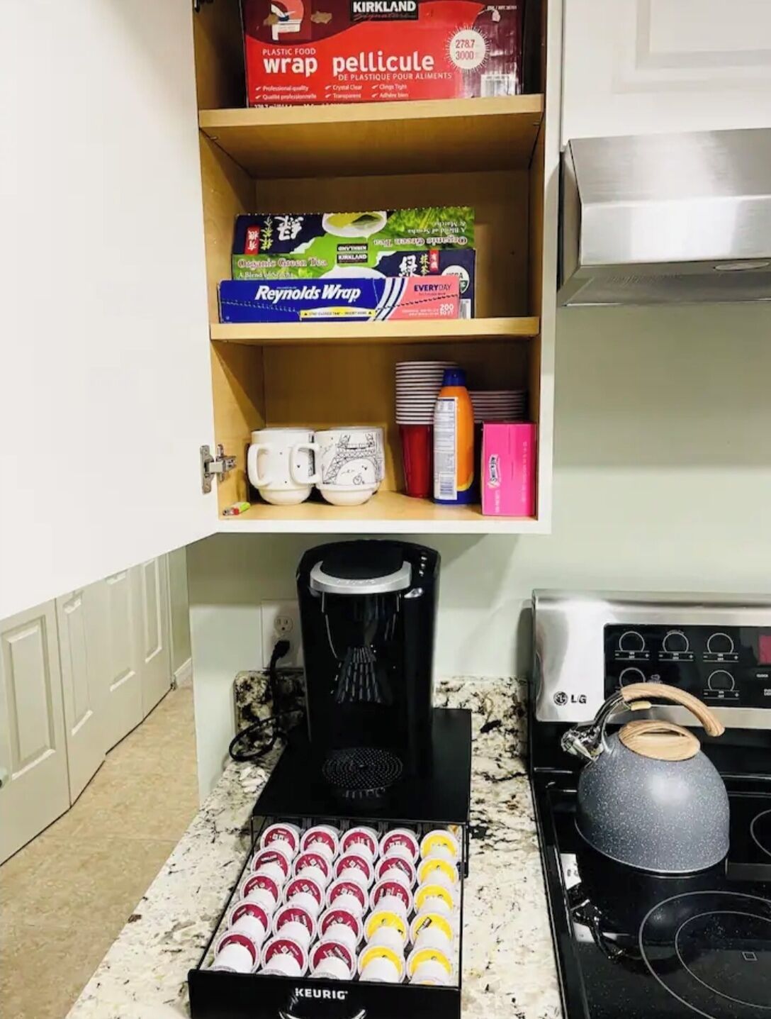 Een keuken met een koffiezetapparaat, waterkoker en diverse keukenspullen op het aanrecht.