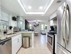 A modern kitchen with stainless steel appliances, a central island, and a view of the outdoors. - Seabreeze garden oasis, jacuzzi, golf, mins ->beaches (Largo)