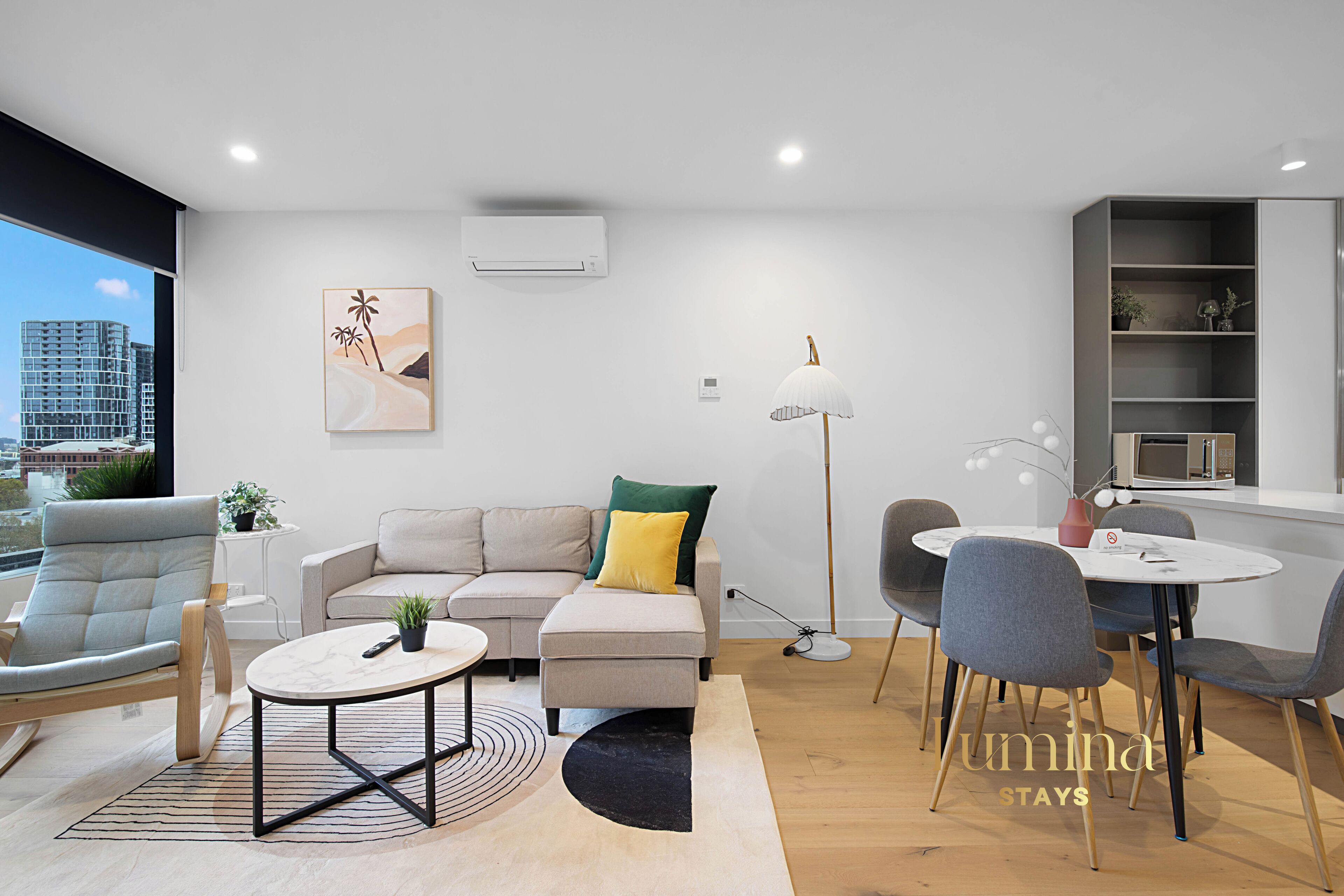 Ein modernes Wohnzimmer mit Sofa, Sessel, Esstisch und Lampe.