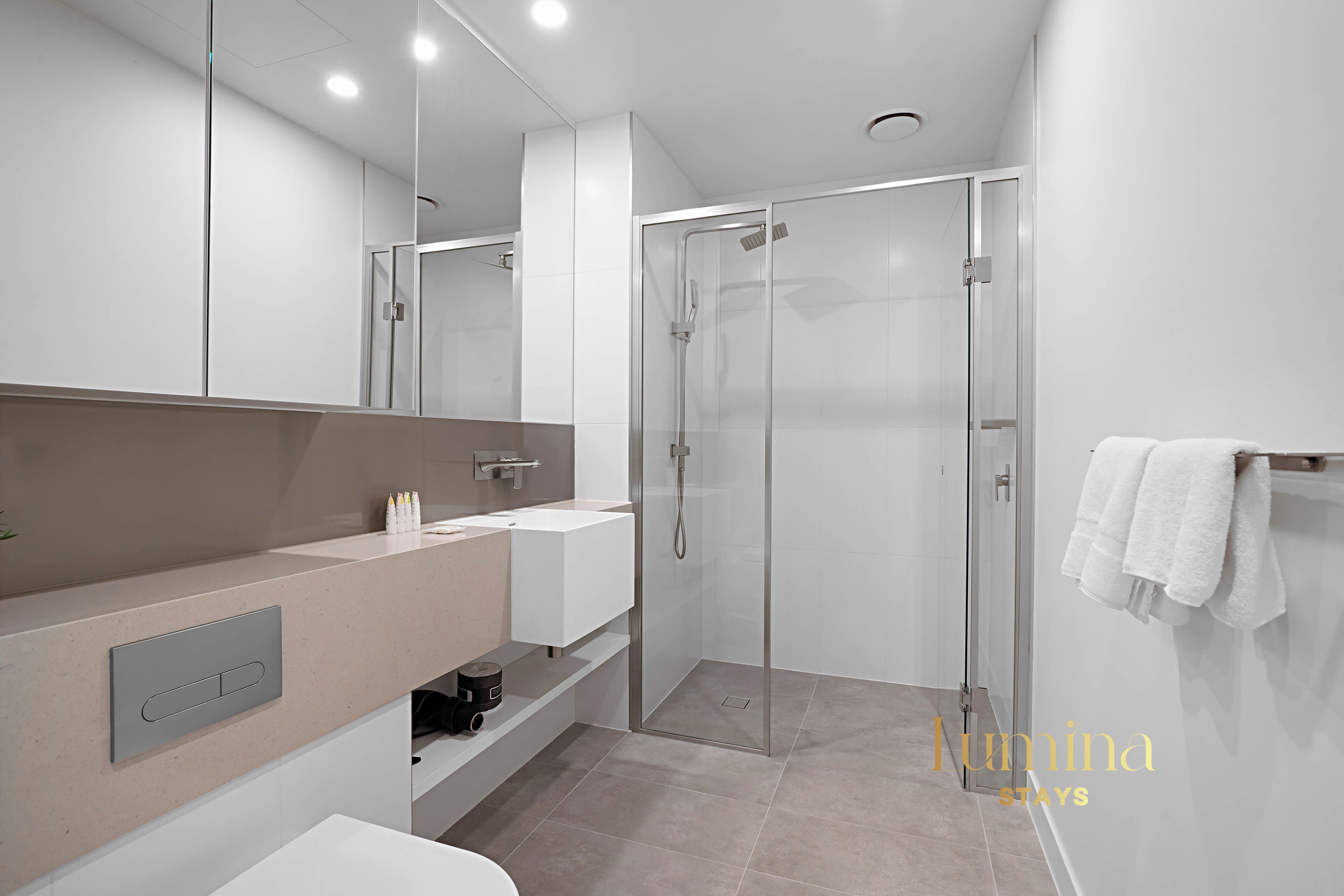Un bagno moderno con box doccia in vetro, lavandino bianco e specchio.