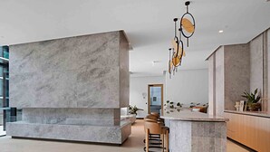 A modern kitchen with marble countertops, a built-in bench, and pendant lighting. - Lumina Stays - Aspire (Melbourne)