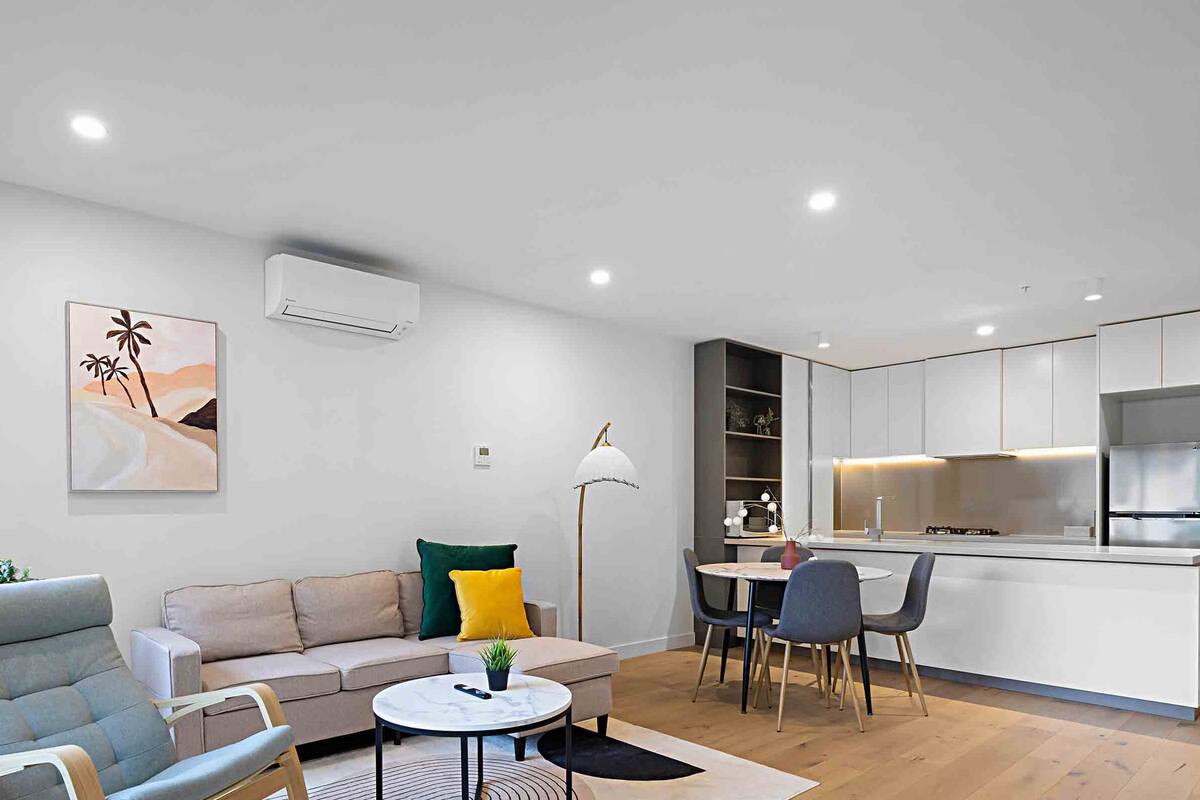 Een moderne woonkamer met een bank, stoelen, een salontafel en een eethoek.