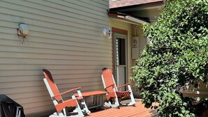 An outdoor patio with two Adirondack chairs and a green metal table.