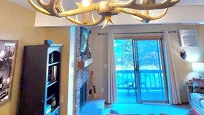 A chandelier with antler design in a living room with a view to the outside. - Not Your Everyday Mini Chalet, foot of Holiday Valley Resort! Walk to Downtown (Ellicottville)