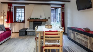 Ein gemütliches Wohnzimmer mit Kamin, einem Essbereich mit Tisch und Stühlen sowie einem an der Wand befestigten Fernseher.