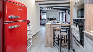 Eine Küche mit einem roten Kühlschrank, Holzschränken, einer Kochinsel und einem eingebauten Ofen.
