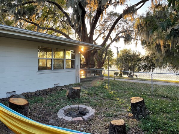 A house with a fenced yard, a hammock, and a fire pit surrounded by tree stumps. - Best sunsets in Winter Haven. Lakefront home 5 minutes from downtown! (Winter Haven)