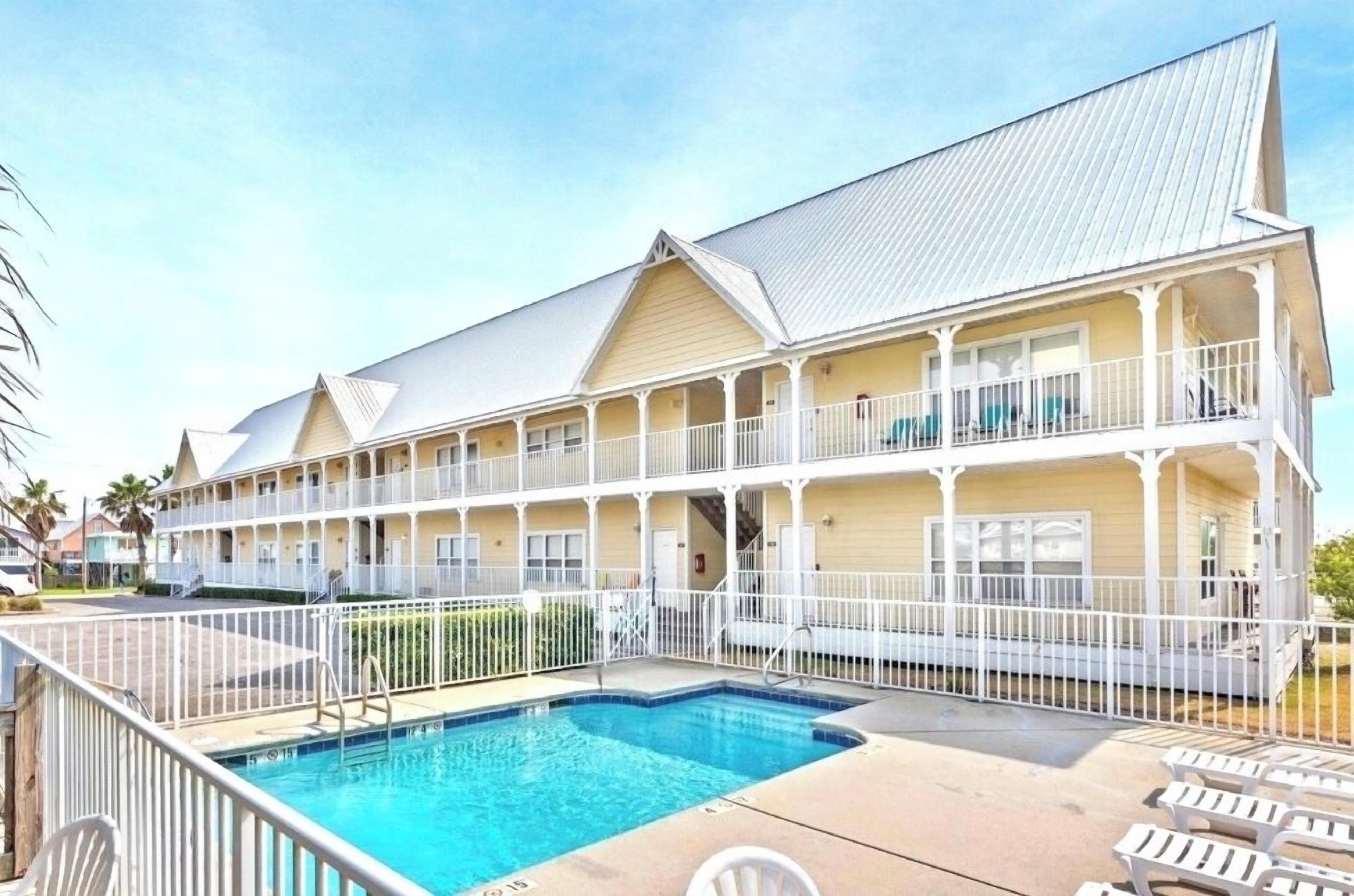 A two-story hotel with a swimming pool and outdoor seating.