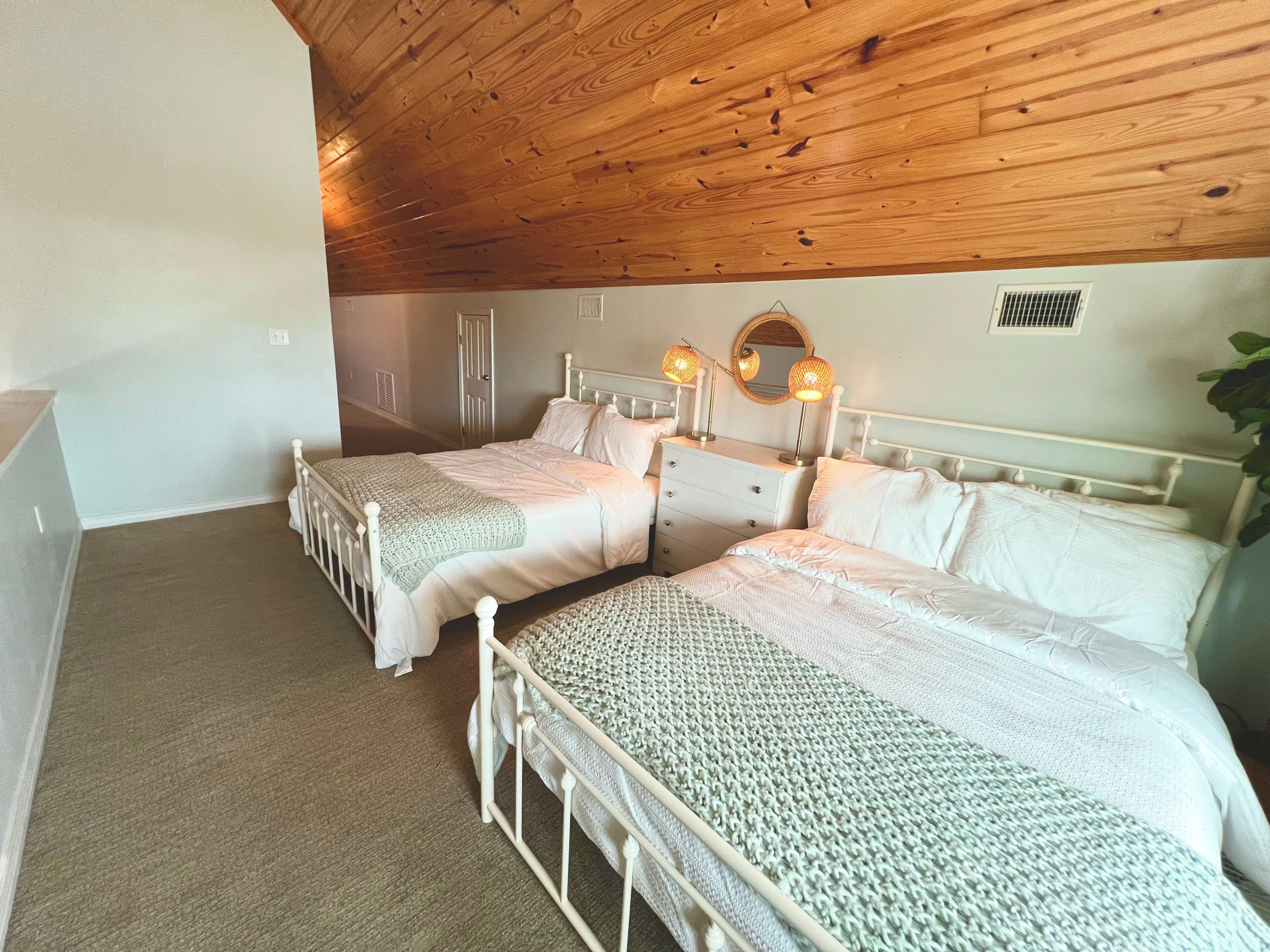 A bedroom with two beds, a dresser, a mirror, and a ceiling fan.