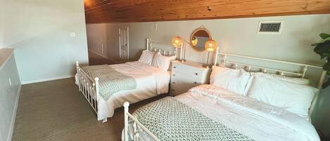 A bedroom with two beds, a dresser, a mirror, and a ceiling fan.