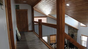 Eine HolztTreppe mit Geländer führt zu einer Erkerzone mit Steinwänden und einem Kamin.