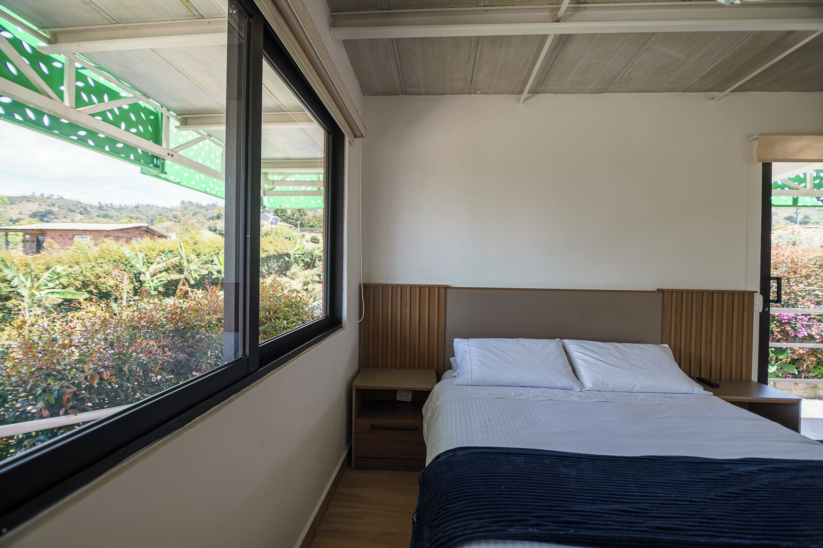 Un dormitorio con cama, ventana y vistas a zonas verdes.