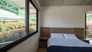 Un dormitorio con cama, ventana y vistas a zonas verdes.