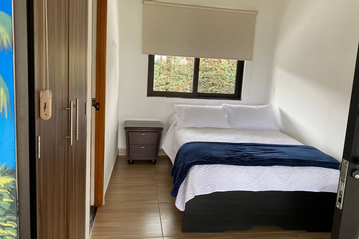 Une chambre à coucher avec un lit, une table de chevet, une fenêtre et une porte.