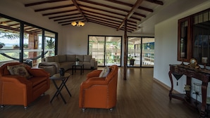 A spacious living area with a high ceiling, large windows, and a view of the outdoors. - Finca Hotel 12 Palmas (Rionegro)