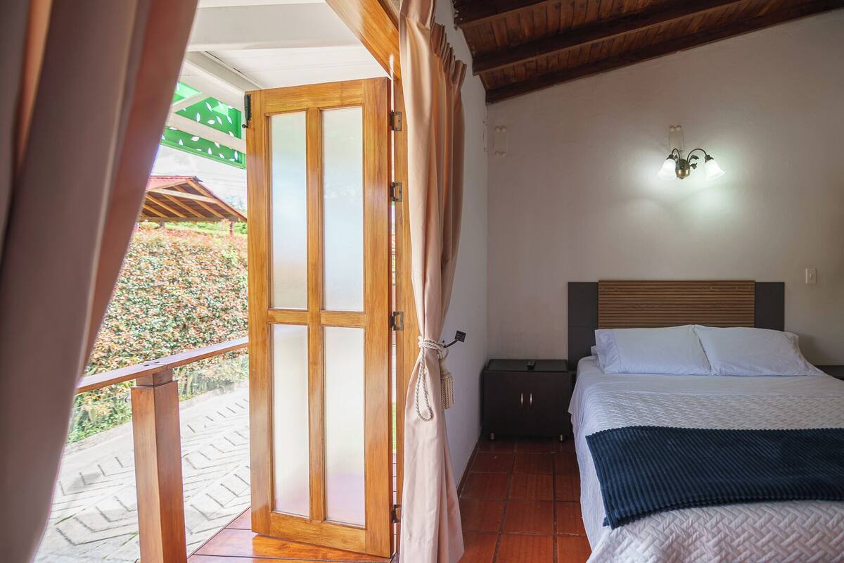 Une chambre à coucher comprenant un lit, une table de chevet, un luminaire fixé au mur et un plafond en bois.