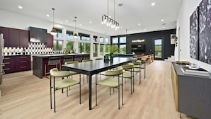 Een moderne keuken met een eethoek, met een groot schiereiland, hanglampen en uitzicht op de omgeving.