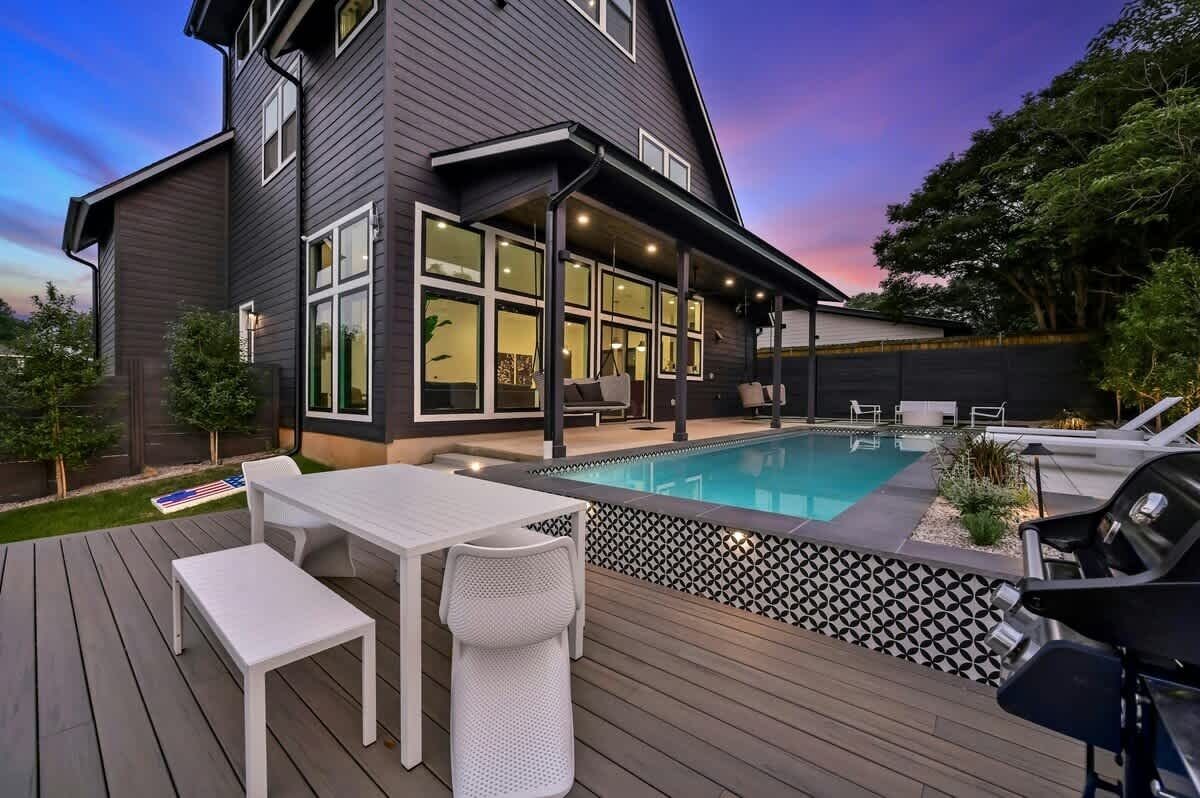 Una casa moderna con piscina, terraza y zona de estar al aire libre.