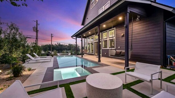 Een modern huis met een zwembad, terrasmeubilair buiten en een overdekte patio.