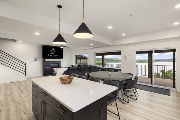 Una cocina moderna con una isla grande, lámparas colgantes negras y vistas al exterior.