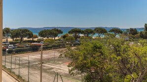 Vista costera con cancha de tenis, árboles y cielo azul despejado.