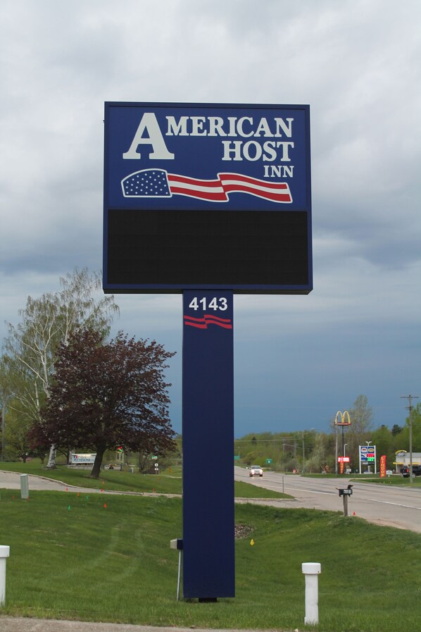 Un grand panneau numérique pour l’hôtel American Host Inn, sur lequel figure le drapeau américain et le numéro « 4143 ».