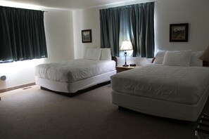 A hotel room with two beds, a nightstand with a lamp, and two framed pictures on the walls.