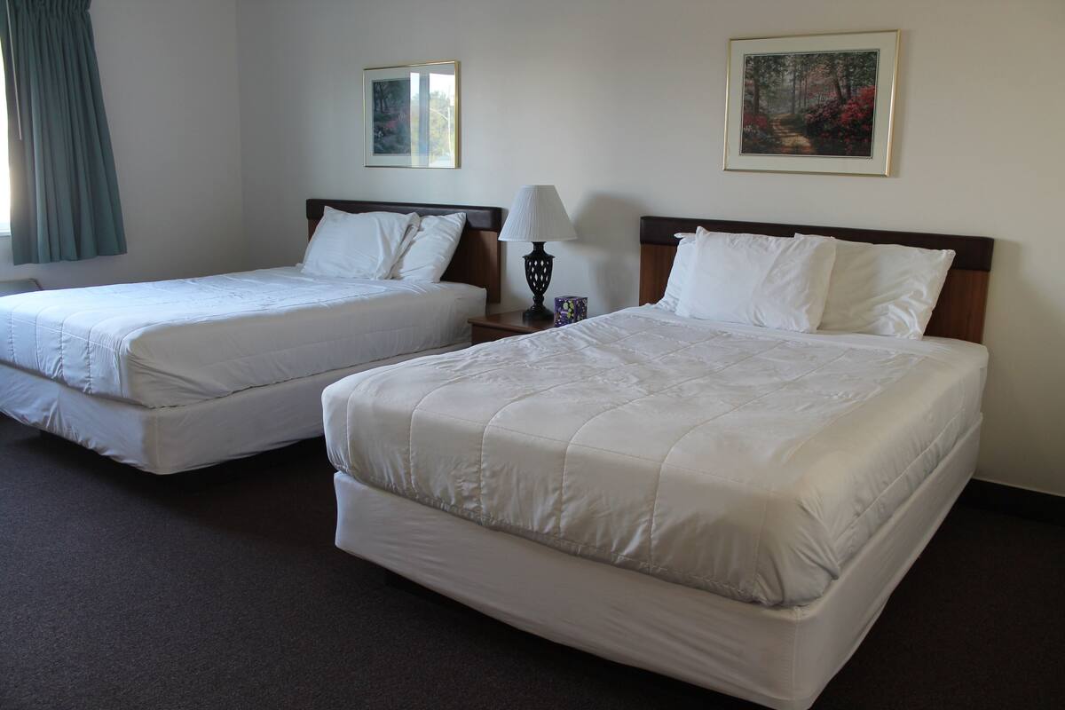 Dos camas individuales con ropa de cama blanca en una habitación de hotel.