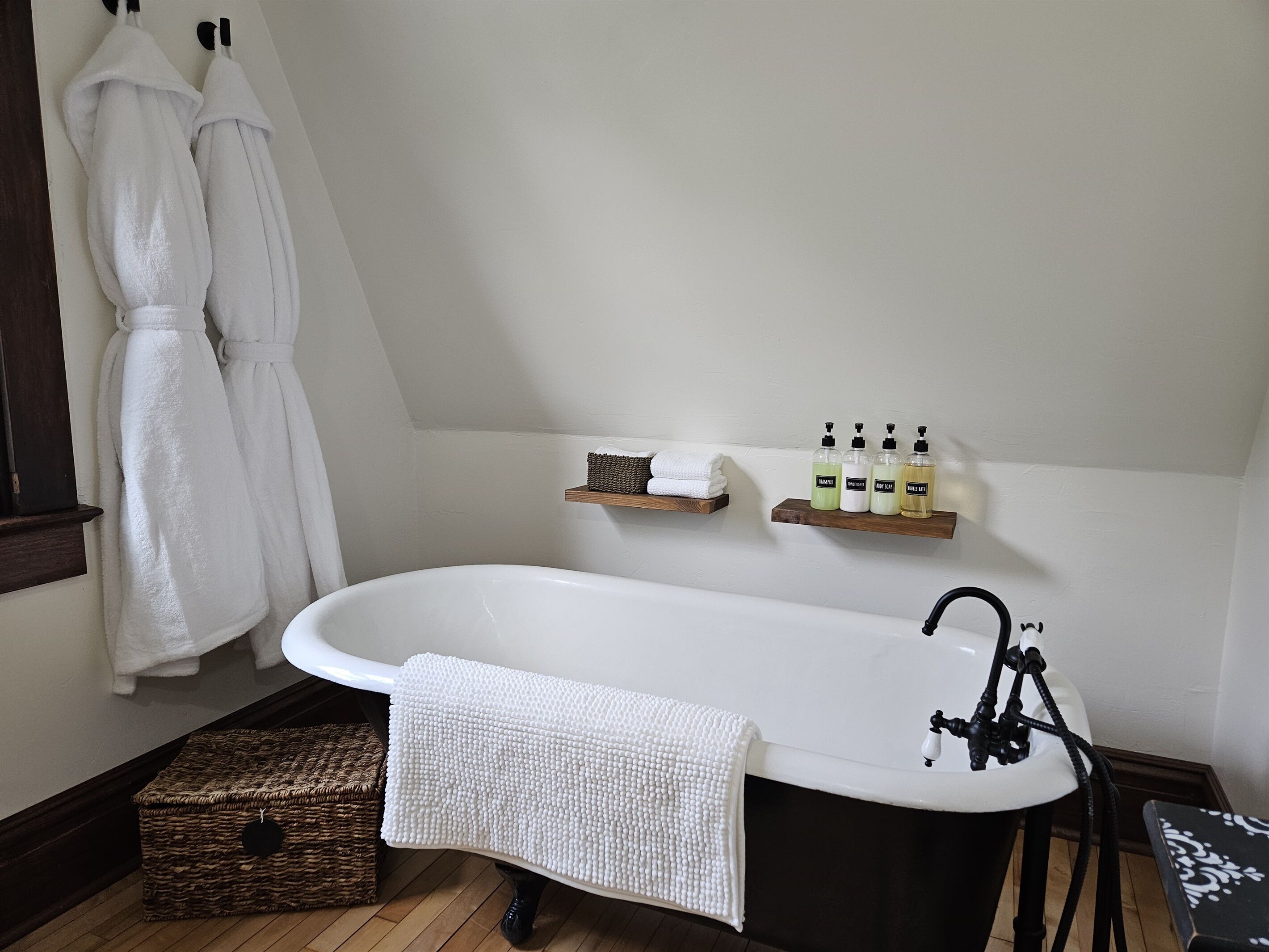 Ein Badezimmer mit freistehender Badewanne, einem hölzernen Ablagefach mit Toilettenartikeln und einem Korbwannen-Korb.