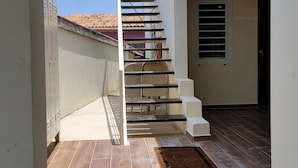 A modern staircase leading to an upper level, with a view of the sky and a tiled floor.