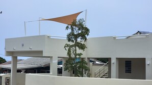 A modern building with a flat roof, a staircase, and a tree in front.