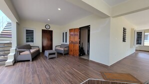 A spacious living area with a wooden floor, two sofas, a small table, and a door leading to another room.