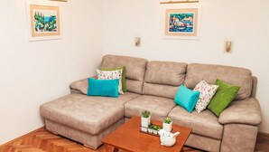 Ein Wohnzimmer mit einem beigefarbenen Ecksofa, einem Holztisch und zwei gerahmten Bildern an der Wand.