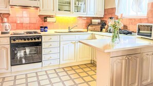 A kitchen with white cabinets, a stove, a sink, and a small refrigerator.