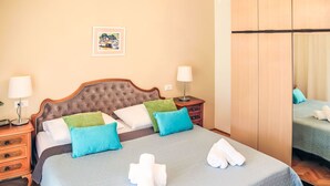 A neatly arranged hotel room with a large bed, two bedside tables, a mirror, and a framed picture on the wall.