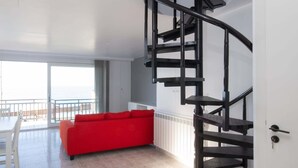 Un intérieur moderne avec un escalier en colimaçon, un canapé rouge et une vue sur l’extérieur.