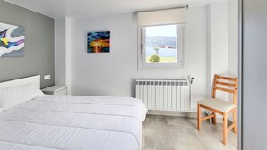 Une chambre à coucher avec un lit, une chaise, un radiateur et une fenêtre donnant sur un beau paysage.
