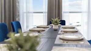 A dining table set with plates, cutlery, and a vase of greenery, with a view of the sky through large windows. - Waterfront Home w/ Views - Hot Tub + Movie Theatre (Bacliff)