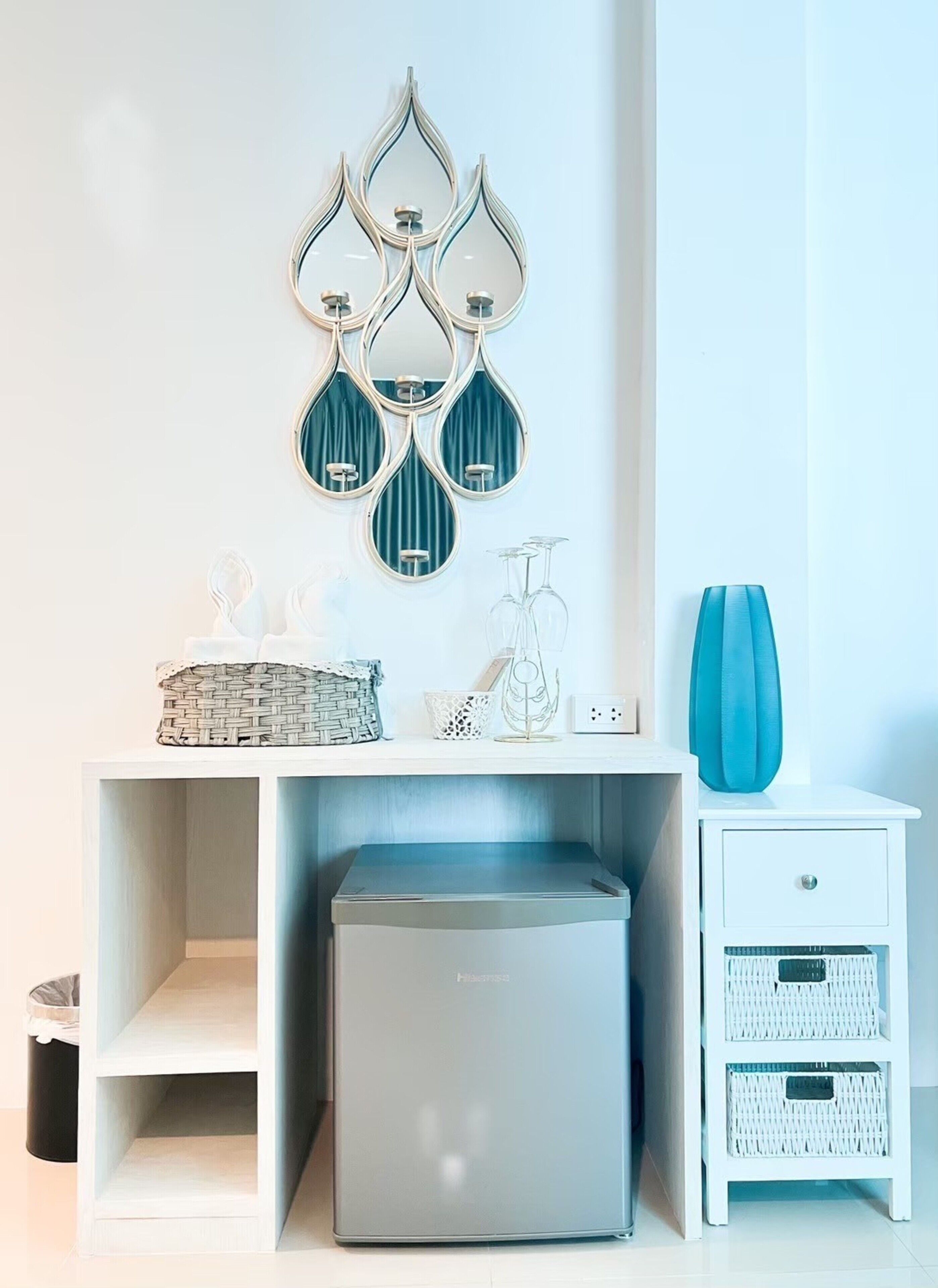 Une chambre moderne avec une console blanche, un meuble de rangement gris et une table de chevet blanche agrémentée de paniers en osier.