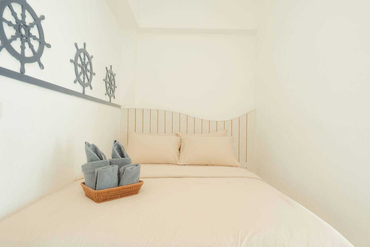Ein ordentlich bezogenes Bett mit einem gestreiften Kopfteil, ein Korb gefalteter Handtücher und drei Schiffsschwielen an der Wand.