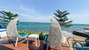 Ein Poolbereich mit zwei Stühlen, einem kleinen Tisch und Blick auf das Meer mit Booten.