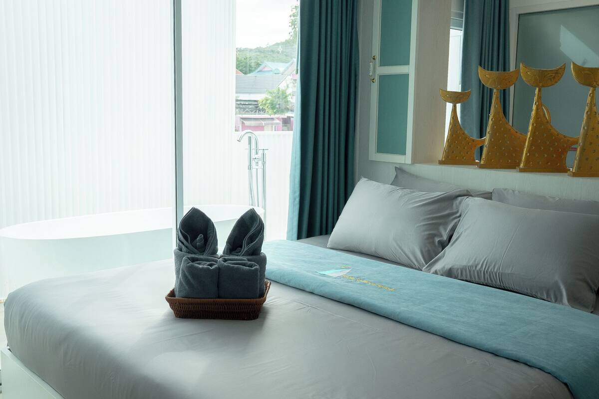 Ein Hotelzimmer mit Bett, einem Vorhangfenster, einer Badewanne und einem Handtuchhalter.