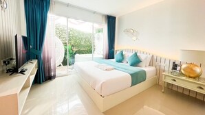Ein modernes Hotelzimmer mit einem großen Bett, einem Schreibtisch und Blick auf einen Garten durch Glastüren.