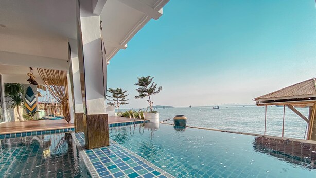 Ein Pool ohne Ende mit freiem Blick auf das Meer, ein überdachter Sitzbereich und ein modernes architektonisches Design.