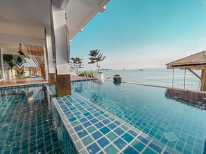 Ein Pool ohne Ende mit freiem Blick auf das Meer, ein überdachter Sitzbereich und ein modernes architektonisches Design.