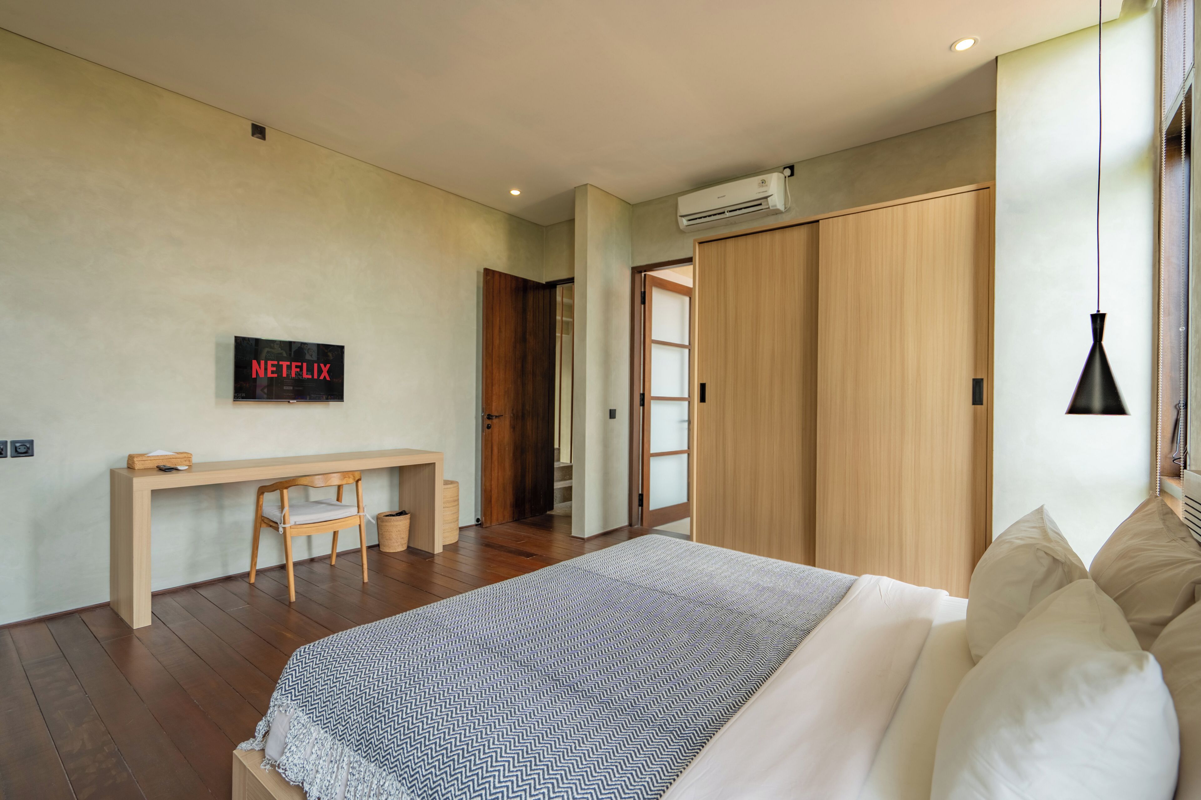 A modern bedroom with a bed, a desk, and a wardrobe.