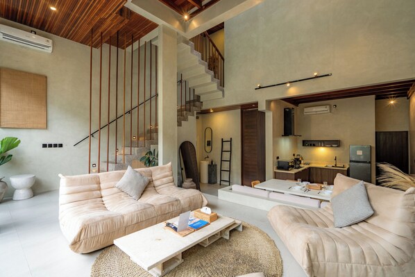 A spacious living area with a sofa, coffee table, and a staircase leading to an upper level.