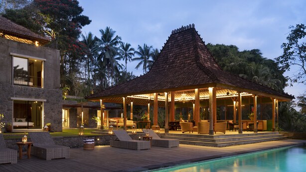 Un resort lujoso con piscina, mobiliario exterior y un patio cubierto.