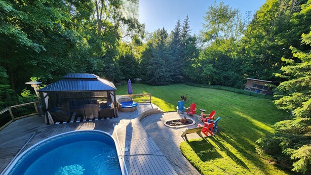 Un patio trasero con piscina, terraza y zona de estar al aire libre.