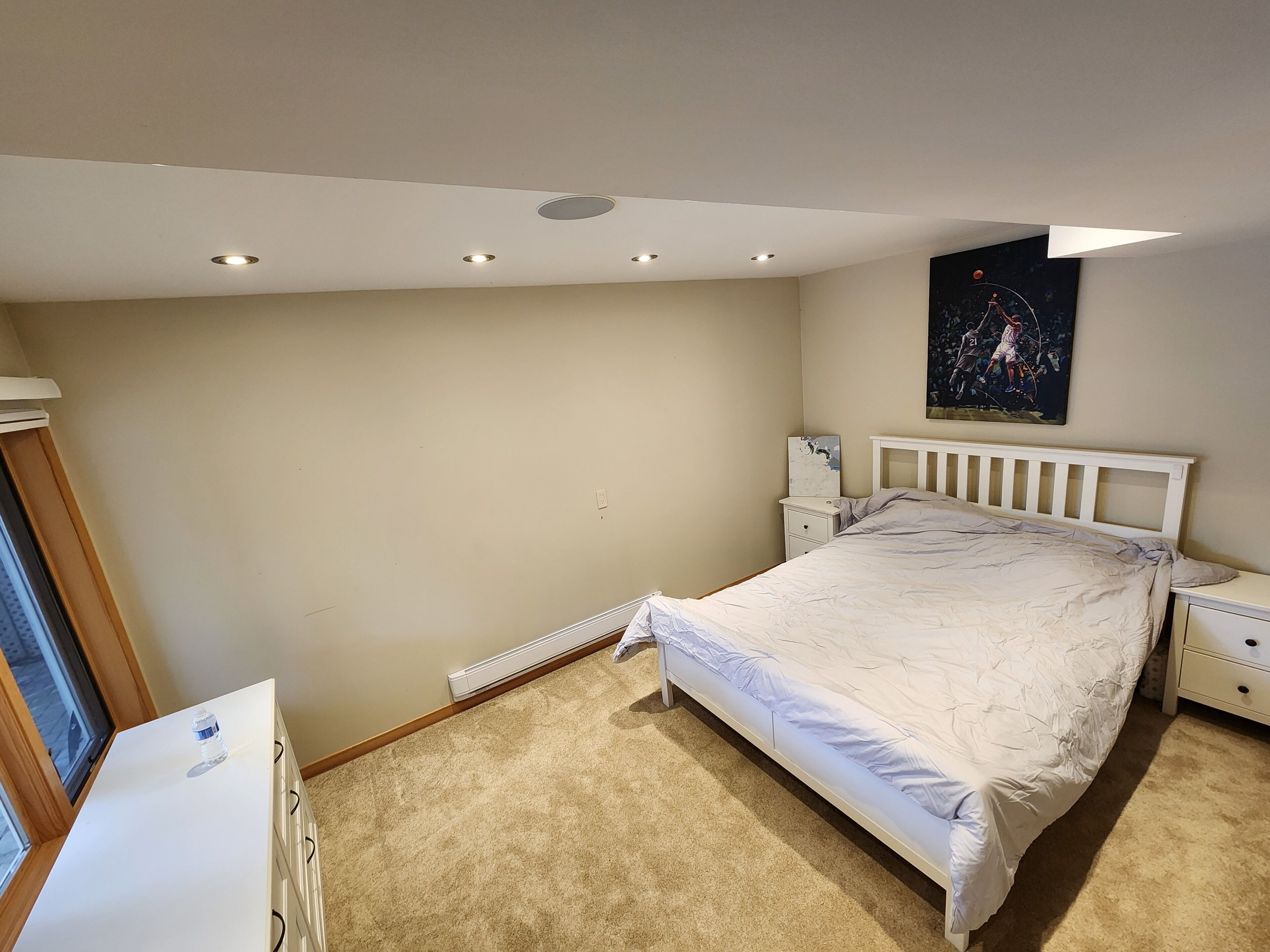 Une chambre à coucher avec un lit, des tables de chevet, un radiateur et un tableau au mur.